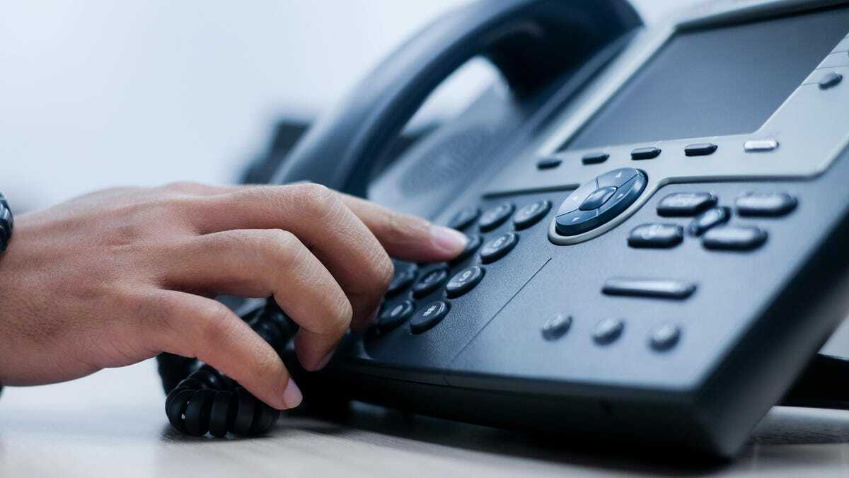 person hitting button on phone system